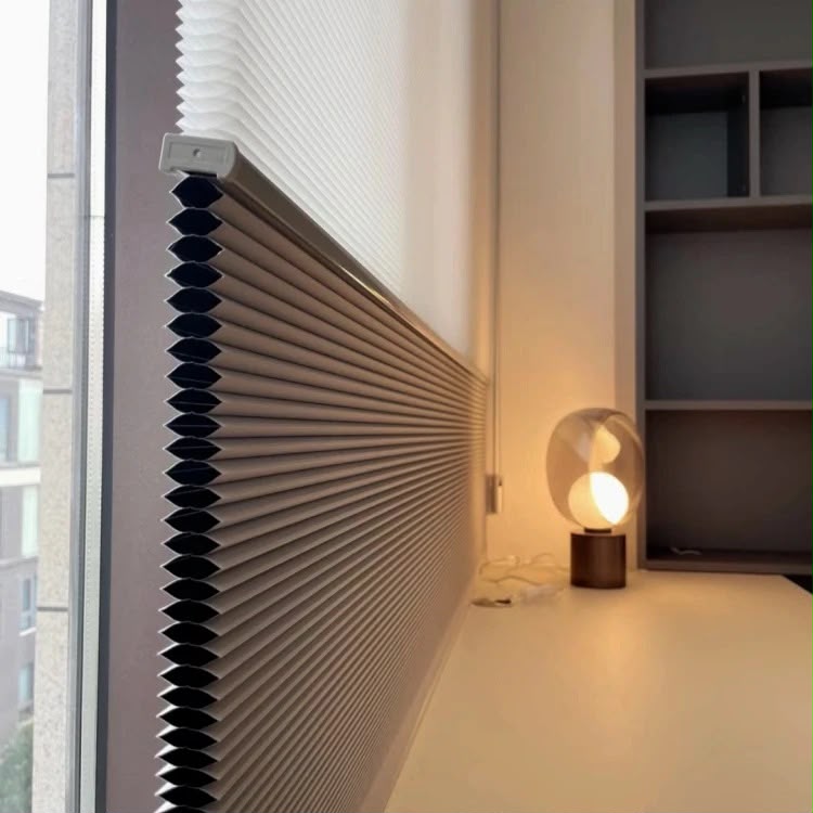 Motorised cellular shade blinds by a window